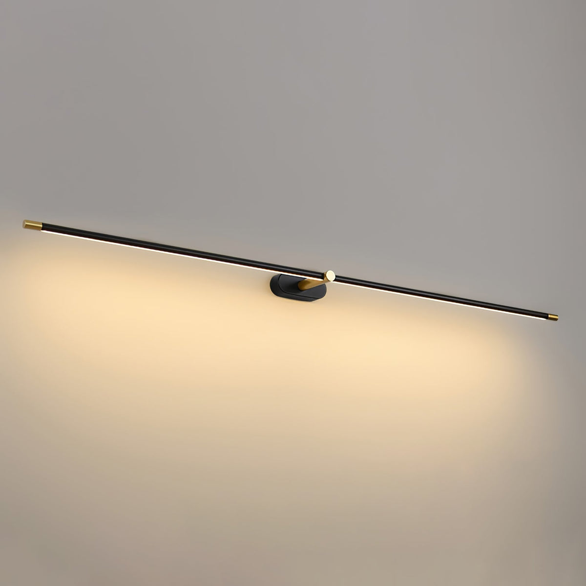 A Vestra Minimalist Linear Rechargeable Wall Lamp in black with gold accents, angled and emitting warm LED light against a plain grey wall. This modern metal wall sconce is ideal for contemporary interiors.