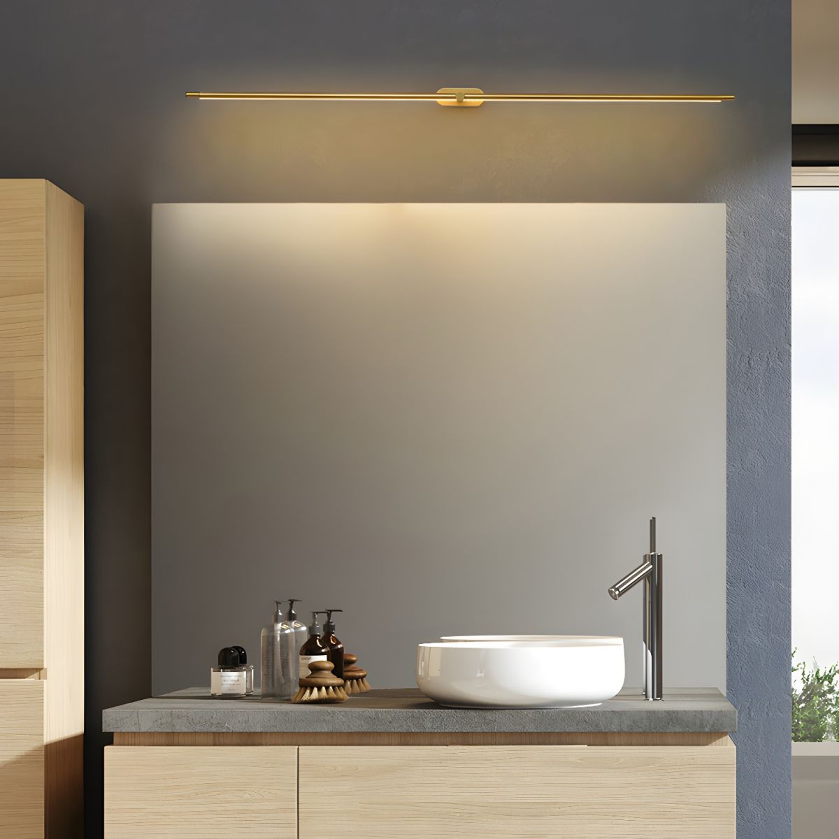 Vestra Minimalist Linear Rechargeable Wall Lamp in gold finish, mounted above a mirror in a modern bathroom with a wooden vanity and white bowl sink.