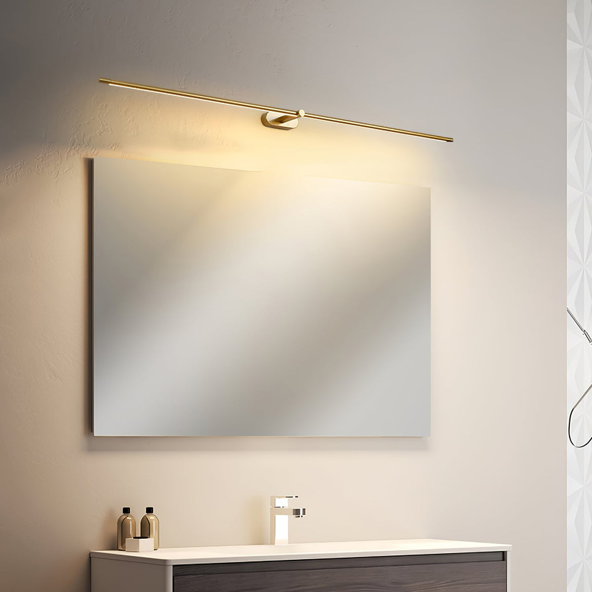 Vestra Minimalist Linear Rechargeable Wall Lamp in gold metal with LED finish, installed diagonally above a rectangular mirror in a bathroom vanity with a dark wood cabinet and white countertop.