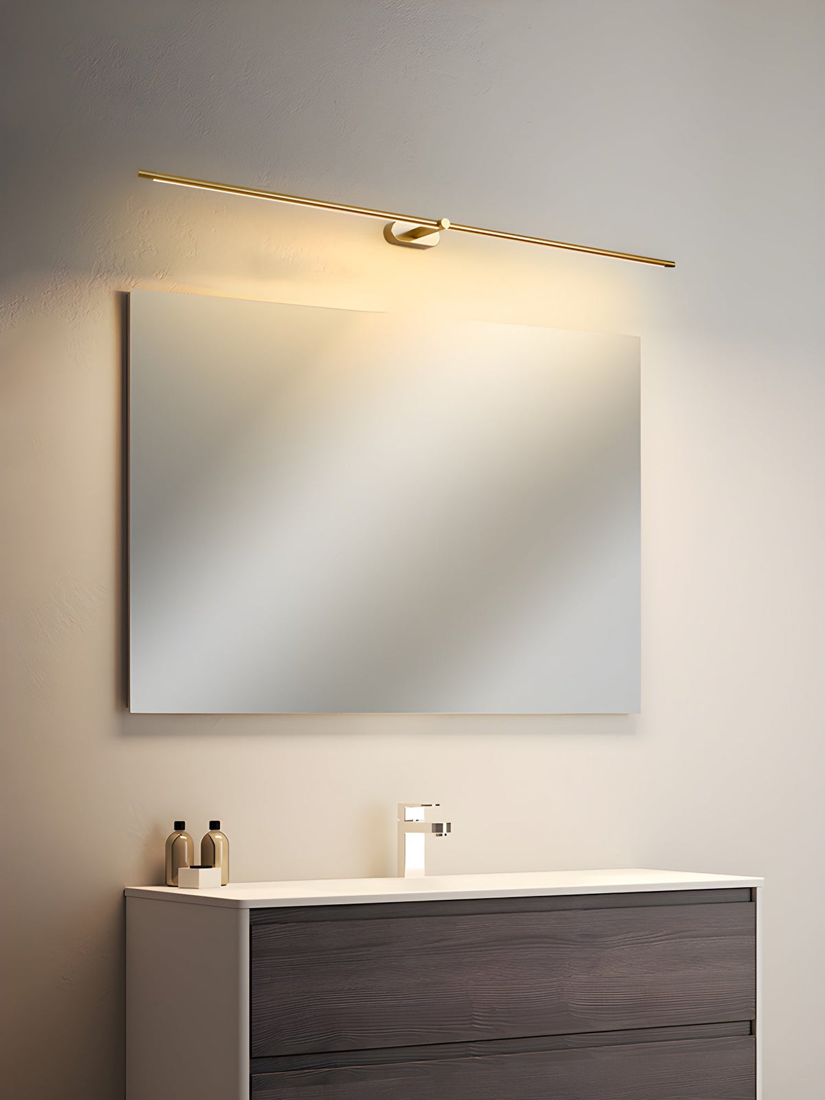 Vestra Minimalist Linear Rechargeable Wall Lamp in gold finish, mounted above a square mirror in a modern bathroom with a dark wood vanity.