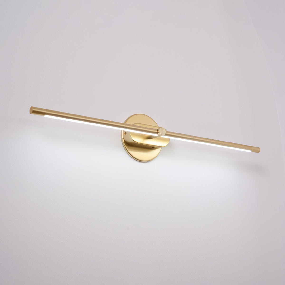 Vestra Minimalist Linear Rechargeable Wall Lamp in gold finish, emitting cool white LED light, mounted on a plain white wall.