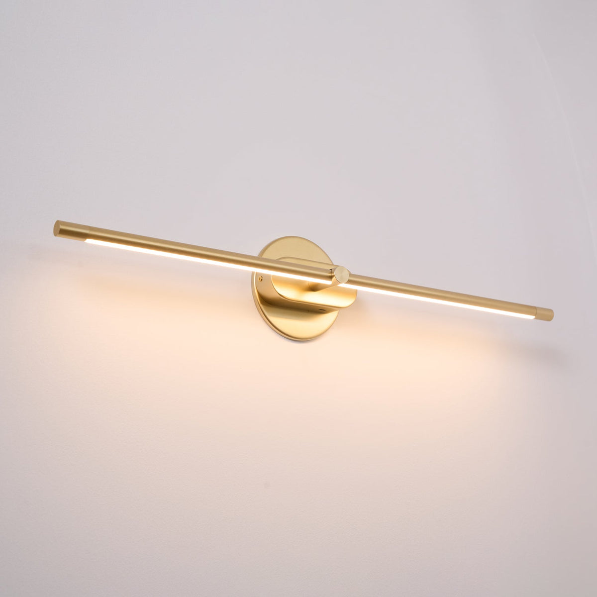 Vestra Minimalist Linear Rechargeable Wall Lamp in gold finish, emitting warm white LED light, mounted on a plain white wall.