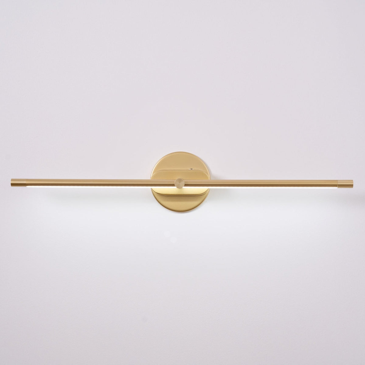 Vestra Minimalist Linear Rechargeable Wall Lamp in gold finish, unlit, featuring a circular base mounted on a white wall.