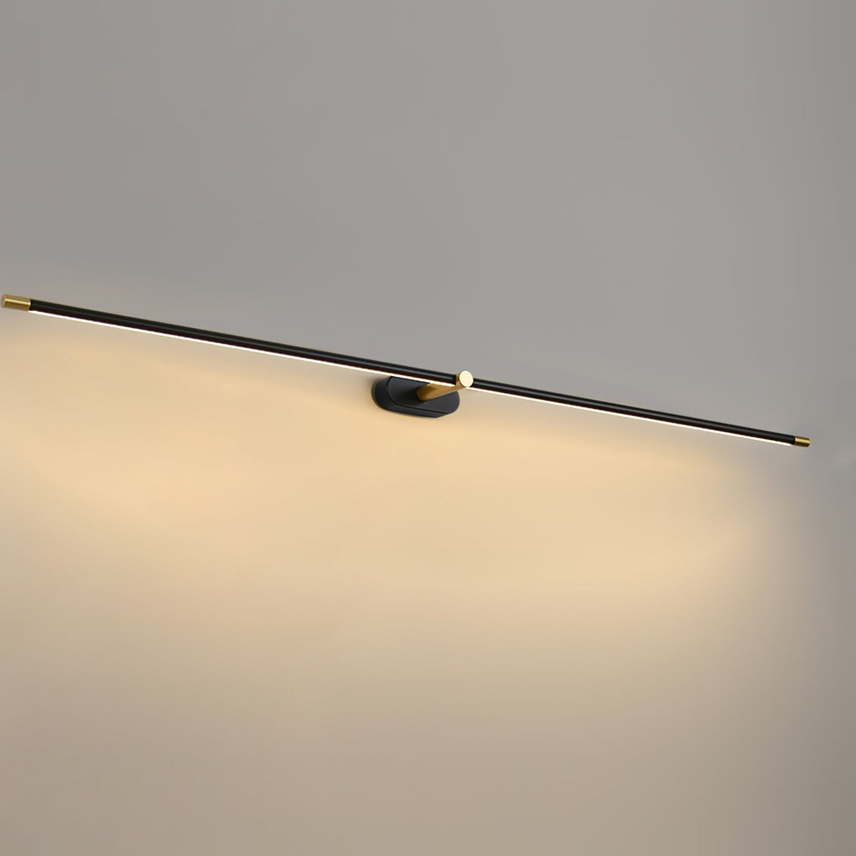 A Vestra minimalist linear rechargeable wall lamp in black metal finish with gold accents, illuminated with warm LED light, mounted on a light grey wall.