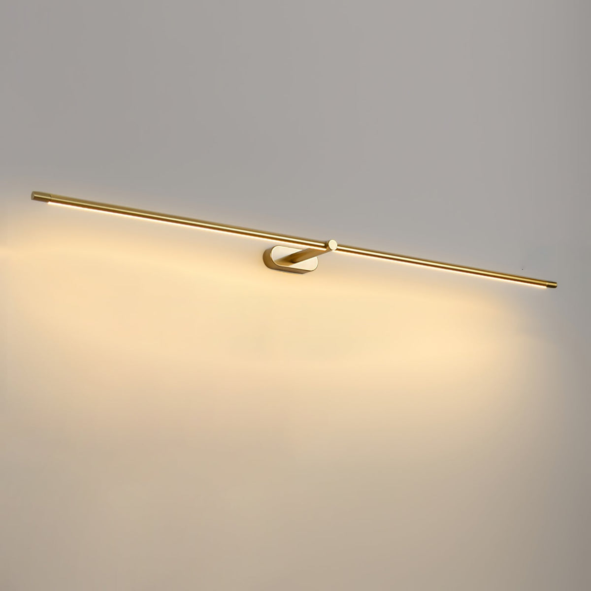 A Vestra minimalist linear rechargeable wall lamp in gold metal finish, illuminated with warm LED light, mounted on a light grey wall.